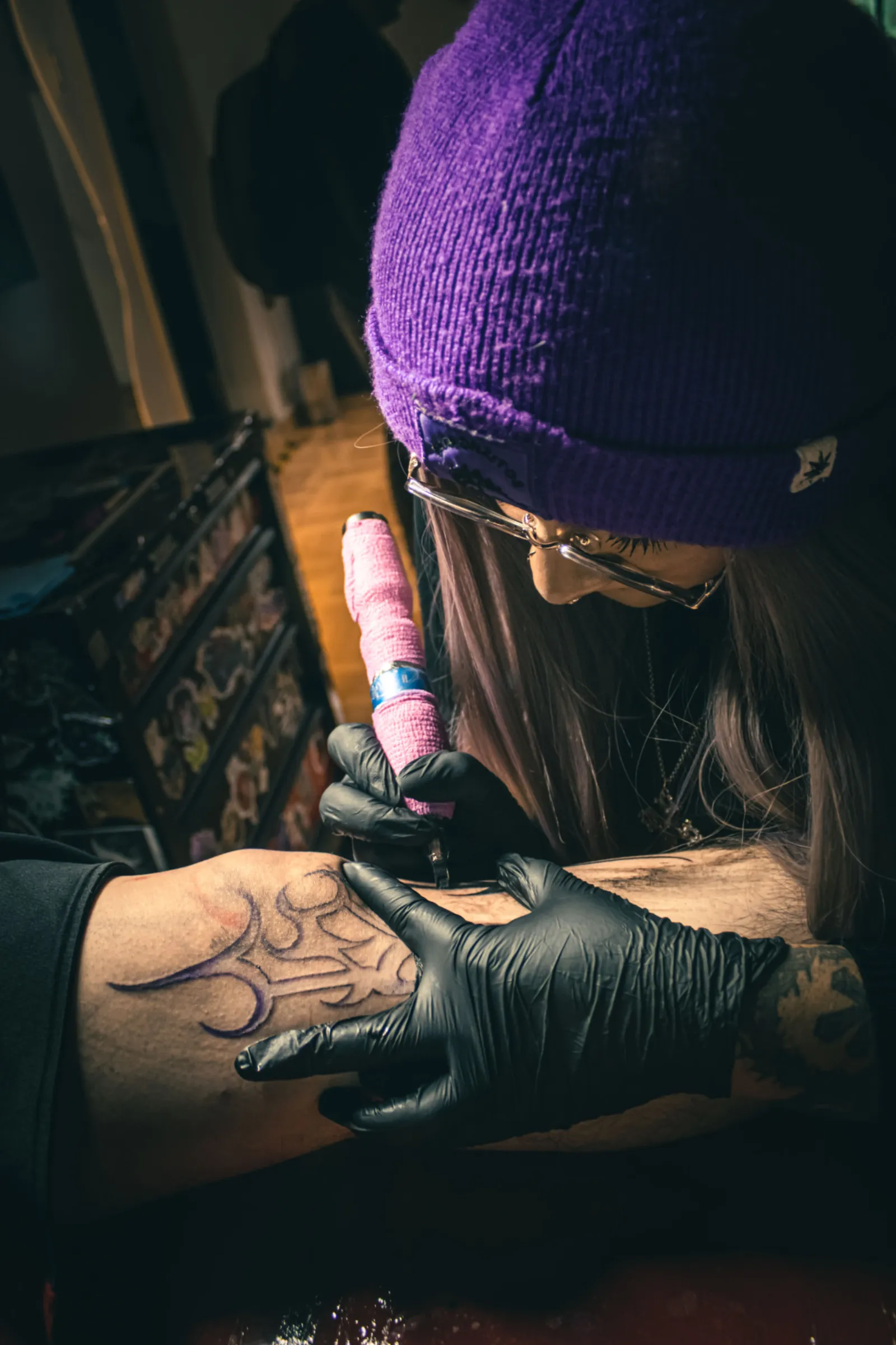 Tattoo Artist konzentriert sich auf eine Linienarbeit am Arm einer Kundin